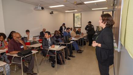 Instructor at head of classroom, speaking