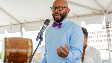Asm. Gipson on stage at microphone, speaking 