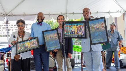 Group photo of commemorative art work being held up for display
