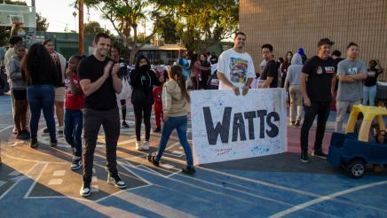 Happy attendees holding a Watts banner with multiple signatures