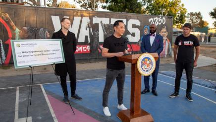 Guest speaker at podium, speaking, with large check on stand at left