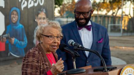Guest speaker at podium, speaking, with Asm. Gipson close-by, listening on