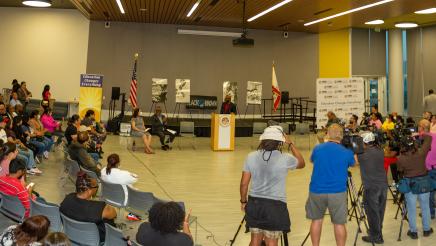 Panoramic view of those in attendance and media coverage