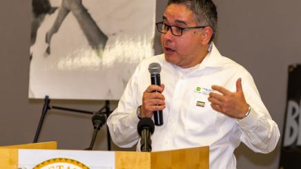 Carlos Torress, Executive Director of The LGBTQ Center Long Beach at podium, speaking
