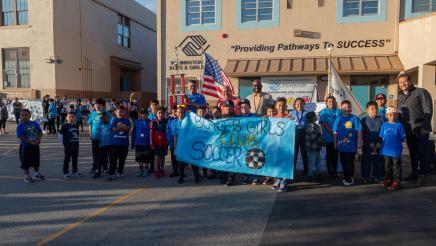 Group photo with Boys & Girls Club Soccer banner held at center