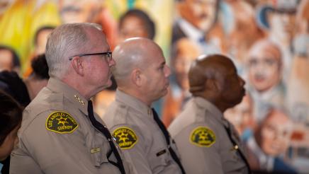 LA Couty sheriffs listening on, with mural in background