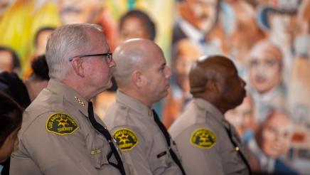 LA Couty sheriffs listening on, with mural in background