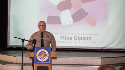 Sheriff at podium, speaking, with slideshow in background