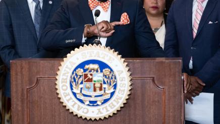 Asm. Gipson at podium, speaking, as Rep. Justin Jones listens on