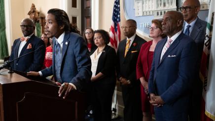 Rep. Justin Jones at podium, speaking, flanked by legislators and other guests