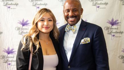 Asm. Gipson and honoree with brand wall in background, featuring event logo