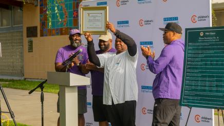 Guest holding up award as group members applaud