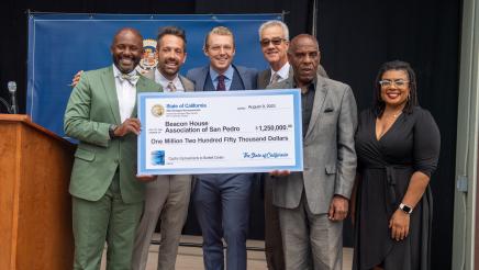 Asm. Gipson, Sen. Bradford and others onstage, holding large ceremonial check