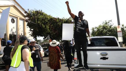 Asm. Gipson standing on bumper of truck, shouting and holding up fist