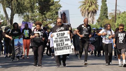 Asm. Gipson jogs alongside fellow marchers, some holding signs and a banner
