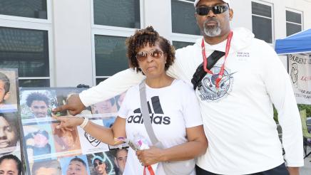 Couple pointing to collage of headshots of shooting victims