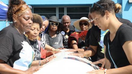 Asm. Gipson and participants holding onto coffin