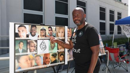 Asm. Gipson points to collage of headshots of shooting victims