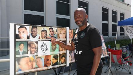 Asm. Gipson points to collage of headshots of shooting victims