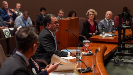 Wide view of five witnesses, one providing testimony