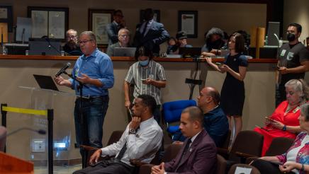 Audience member speaking at podium while other audience members listen on