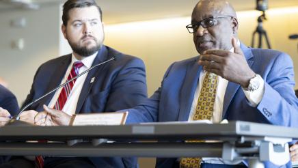 Cpt. Ezra Sly Hunter (Intl. Org. of MM&P Ports), seated with Kyle Burleson at left, speaking