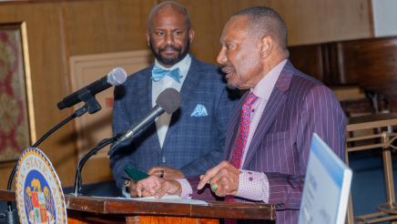 Asm. Gipson listens on as hospital administrator speaks at podium