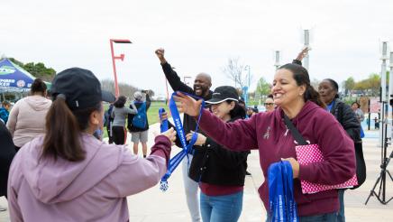 Asm. Gipson cheering participants on as participant is handed medal