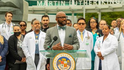 Asm. Gipson at podium, speaking, with hospital staff in background