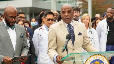 Sen. Bradford at podium, speaking, with hospital staff in background