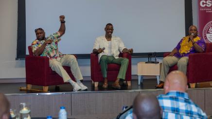 Three guest speakers seated onstage, speaking to attendees