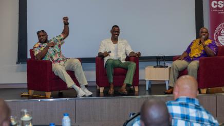 Three guest speakers seated onstage, speaking to attendees