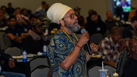 Audience member standing, speaking into microphone