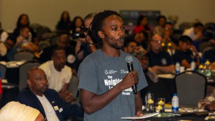 Audience member standing, speaking into microphone