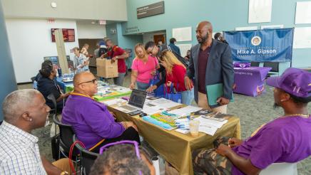 Asm. Gipson speaking with volunteers at resource table