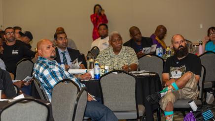 Multiple fathers seated at tables, listening on