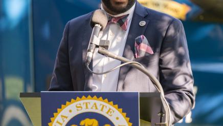Asm. Gipson at podium, speaking into microphone