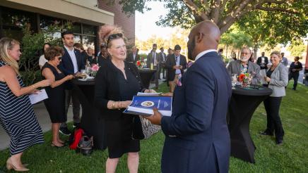 Asm. Gipson holding stack of reports and handing one to an attendee