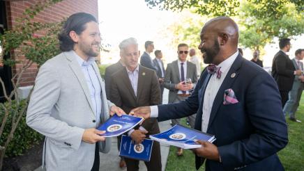 Asm. Gipson holding stack of reports and handing one to an attendee