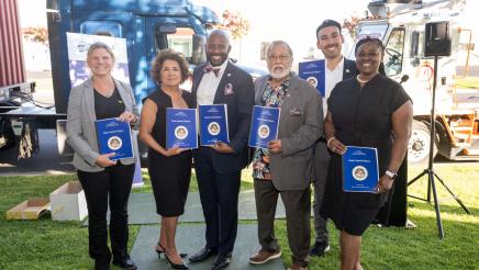 Group photo of Asm. Gipson with attendees, all displaying reports