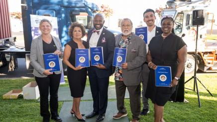 Group photo of Asm. Gipson with attendees, all displaying reports