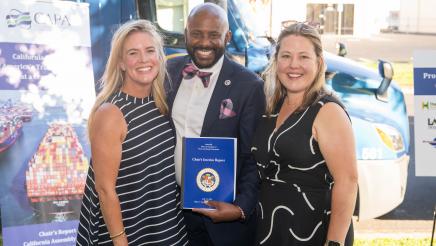 Asm. Gipson posing with two attendees and displaying report