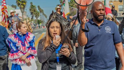 Asm. Gipson holding up megaphone as marcher speaks into microphone