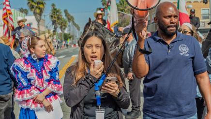 Asm. Gipson holding up megaphone as marcher speaks into microphone