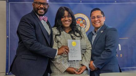 Asm. Gipson with guest speakers, holding signed bill