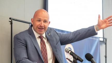 Guest speaker at podium, speaking and holding up one arm