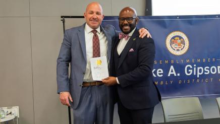 Asm. Gipson with guest speaker, holding signed bill