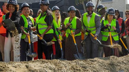Asm. Gipson and others wearing hard hats and shoveling dirt during ceremonial groundbreaking