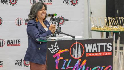 Honoree speaking at podium with logo backdrop in background