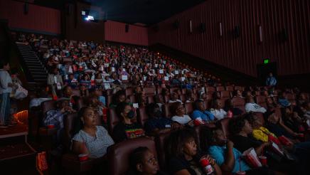 Wide view of theater filled with audience members watching film